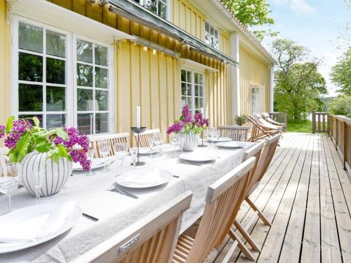 a wooden deck with a long table with purple flowers at 12 person holiday home in HOVA in Hova