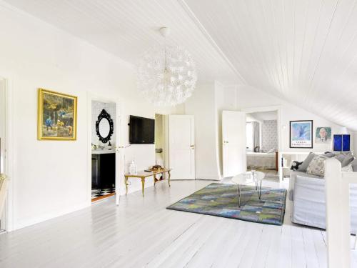 a white living room with a couch and a chandelier at 12 person holiday home in HOVA in Hova