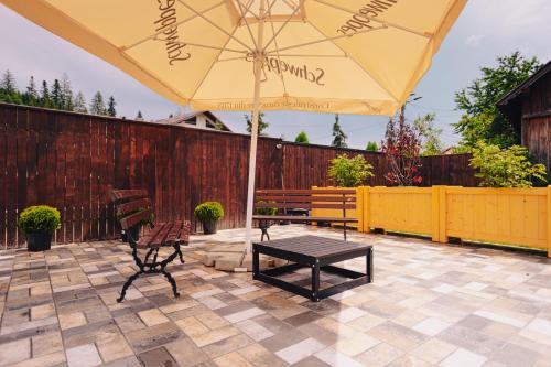 a patio with an umbrella and two chairs and a bench at Chalet 173 in Gura Humorului