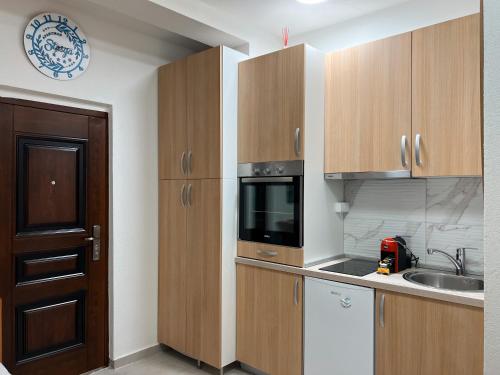 a kitchen with wooden cabinets and a microwave at Apartman Stasija in Tivat