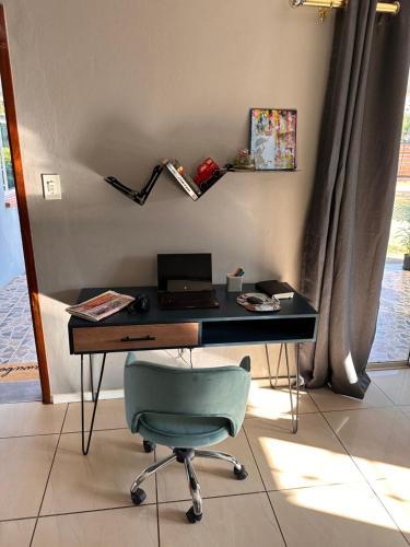 a desk with a laptop and a chair in a room at WeMukelekile (you are welcome) in Lobamba