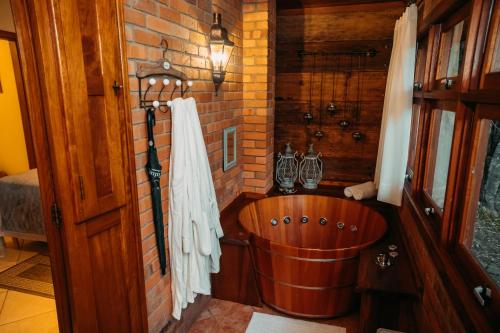 a wooden tub in a room with a brick wall at Villa Tuiuty Pousada de Charme in Bento Gonçalves
