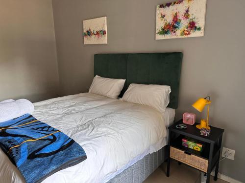 a bedroom with a bed with a green headboard and a table at WeMukelekile (you are welcome) in Lobamba