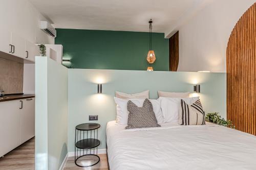 a bedroom with a white bed and a green wall at Japandi, Appartamento Zona Porto Mediceo Livorno in Livorno