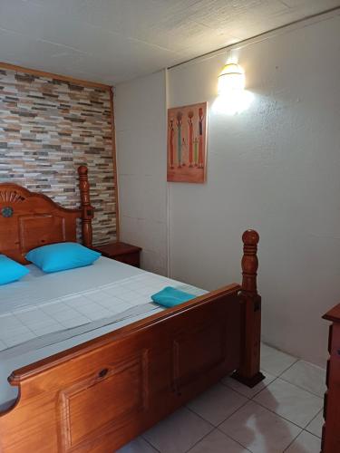 a bedroom with a wooden bed with blue pillows at Meryem in La Trinité