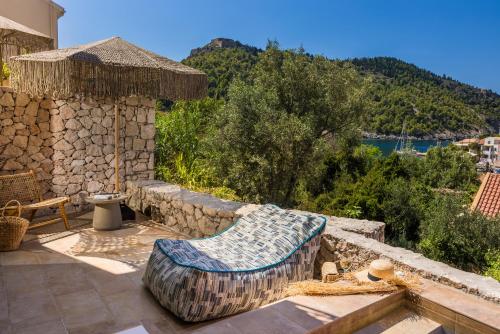 a patio with a couch and a stone wall at Chromata Assos Villas Kefalonia in Asos