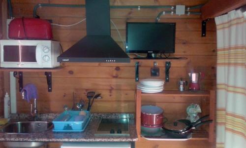 a small kitchen with a microwave and a stove at Cabañas Negratín in Cuevas del Campo
