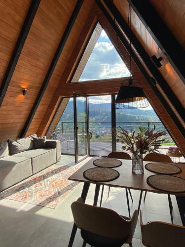 ein Wohnzimmer mit einem Tisch und Stühlen sowie einem großen Fenster in der Unterkunft Mirador Cottage in Slawske