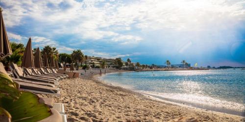 a beach with chairs and umbrellas and the ocean at Charmante Maison entre Cannes et Nice in Le Bar-sur-Loup