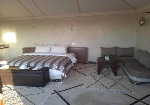 a bedroom with a bed and a couch and a table at Desert Luxury Camp in Mhamid