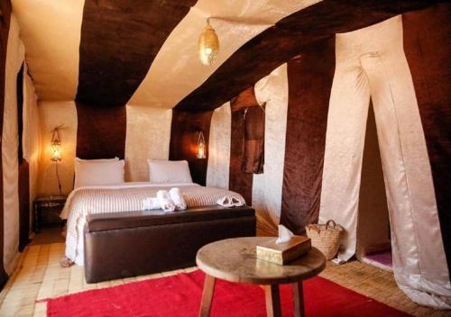 a bedroom with a bed and a table in a room at Desert Luxury Camp in Mhamid