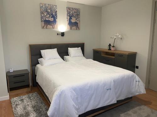 a bedroom with a large bed with white sheets at Apartman Mist - Bela Reka Kopaonik in Brzeće