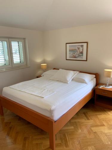 a bedroom with a large bed with white sheets and two lamps at Villa Mara Promajna in Promajna
