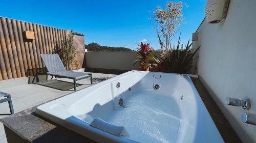 a bath tub sitting on a patio with a chair at Hotel Amantykir in Itajubá
