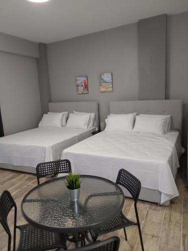 a room with two beds and a table and chairs at Vasiliki Studios Tolo in Tolo