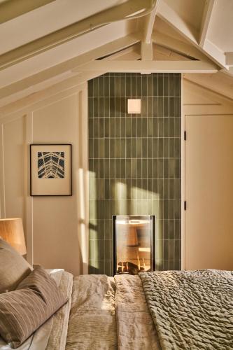 a bedroom with a green tiled wall with a fireplace at Dawn Ranch in Guerneville