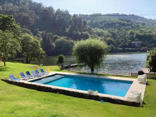 a swimming pool with chairs and a lake at Casa de Rebolfe (Cinfães - Douro) in Cinfães