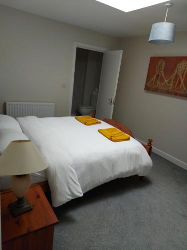 a bedroom with a large white bed with yellow towels on it at Plaza suite 61 B in Bangor