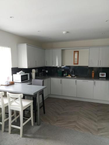 Plaza suite 61 B في بانغور: مطبخ مع دواليب بيضاء وطاولة وكراسي