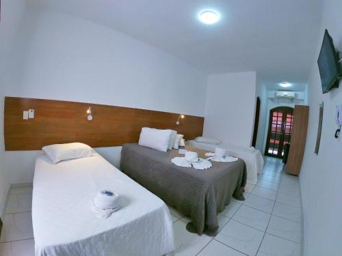 a hotel room with two beds with white sheets at Hotel Marazul in Cananéia