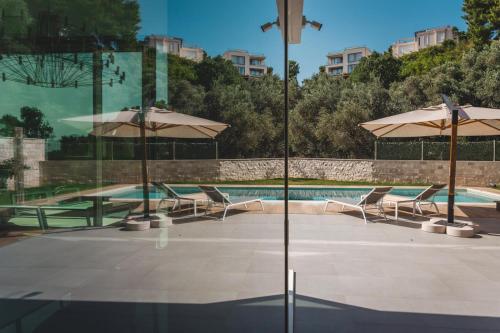 a swimming pool with umbrellas and chairs and a swimming pool at Villa Solaria in Sveti Stefan