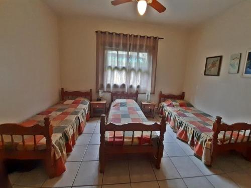 a room with three beds and a window at RIVIERA-CASA FAMILIAR PERTO DA PRAIA-3 QUARTOS-3 BANHEIROS-ATÉ 10 PESSOAS-Módulo 4 in Bertioga