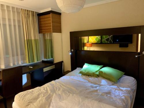 a bedroom with a bed with a desk and green pillows at Zwischen See und Stadt in Klagenfurt