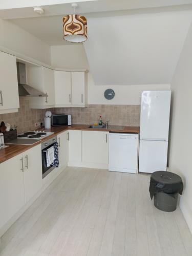 a kitchen with white cabinets and a white floor at Atrium Apartment A in Bangor