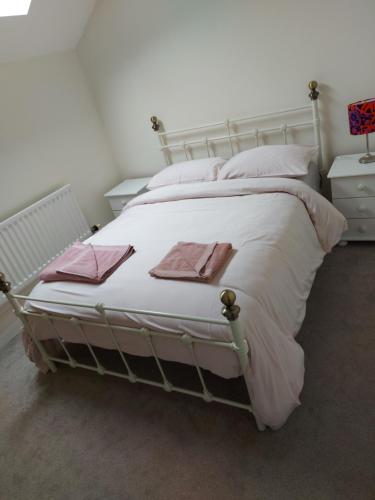 uma grande cama branca com toalhas cor-de-rosa em Atrium Apartment A em Bangor