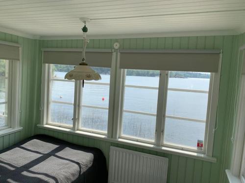 Waterfront house with jacuzzi & jetty in Stockholm في ستوكهولم: غرفة نوم بجدران خضراء ونوافذ بها سرير