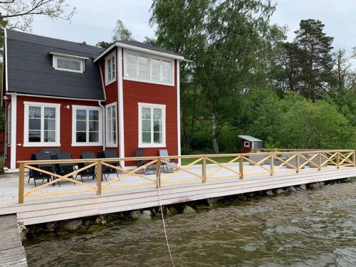 a red house on a dock with a boat in the water at Waterfront house with jacuzzi & jetty in Stockholm in Stockholm
