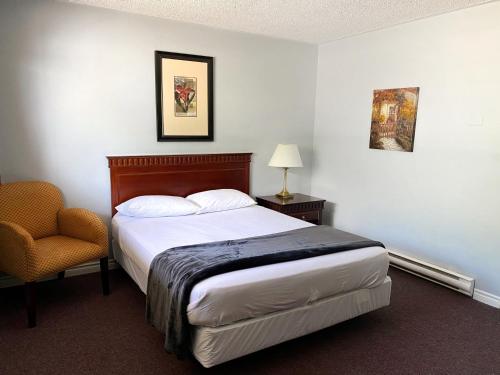 a hotel room with a bed and a chair at The Fort Nashwaak Motel in Fredericton