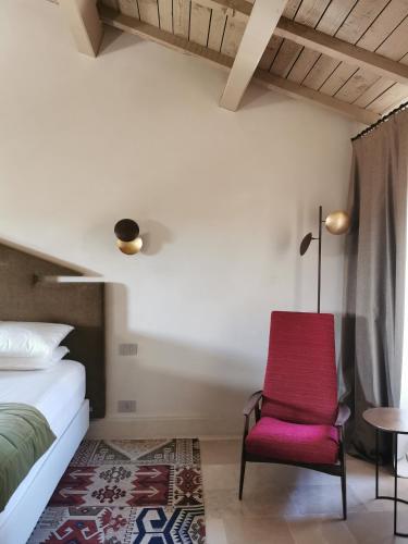 a bedroom with a bed and a red chair at Palazzo Maresgallo Suites & SPA in Lecce