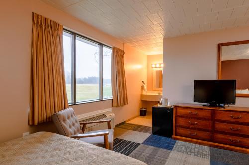 a hotel room with a bed and a flat screen tv at Candlestone Golf and Resort in Belding