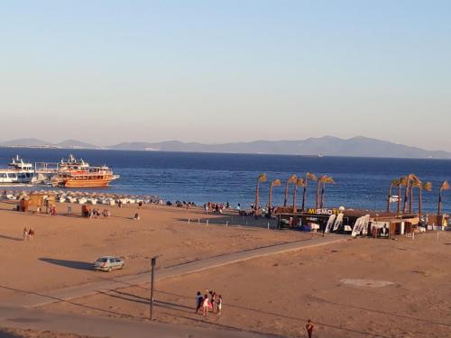 een strand met een groep mensen en boten in het water bij SARIMSAKLI PLAJINA 0 METRE DENİZ MANZARALI LÜX DAİRE in Ayvalık