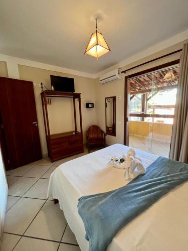 a bedroom with a bed with a teddy bear on it at Pousada Pangea Tropical in Arraial d'Ajuda