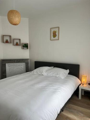 - une chambre avec un lit blanc et une table avec une lampe dans l'établissement Joli appart à 10 minutes de Paris en métro - Parking Offert, à Saint-Ouen