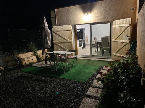 a table and chairs in a yard with a sliding glass door at Studio tout équipé à la nuitée ou plus,proche aéroport Bastia in Lucciana