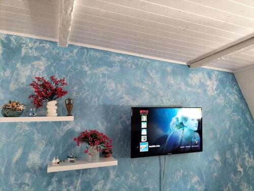 a flat screen tv on a blue wall at Sea Side Attic in Rosolina Mare