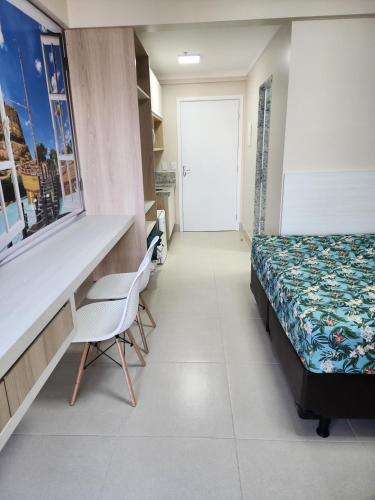 a bedroom with a bed and a desk and a window at RESERVE SEU FLAT E GANHE SUA DIVERSÃO in Caldas Novas