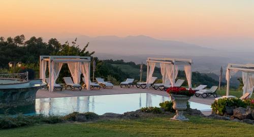 een zwembad met stoelen en een zonsondergang op de achtergrond bij Villa Le Polle di Meletro in Chianni