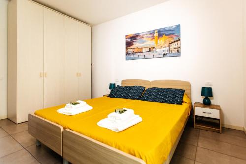 una camera da letto con un letto giallo con due asciugamani di Casa R&R *10' a Piedi da Piazza Del Campo*! a Siena