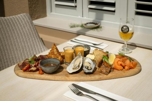 Connemara Sands Hotel & Spa في كليفدين: صينية من المأكولات البحرية على طاولة مع كوب من النبيذ