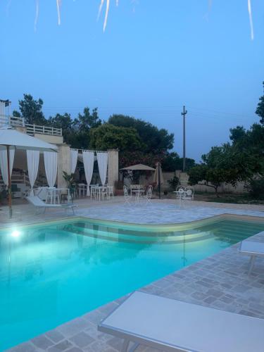 einen Pool mit Tischen und Stühlen in einem Resort in der Unterkunft Antico Casale Il Sambuco in Manduria