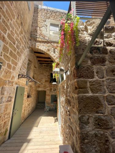 an alley in a stone building with flowers on the wall at Hebi house in ‘Akko