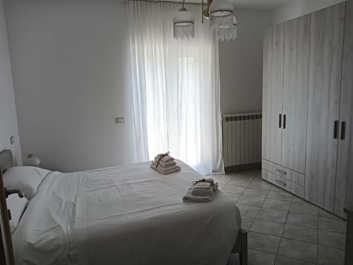 a white bedroom with a bed with towels on it at CASA FRANCESCA in Assergi