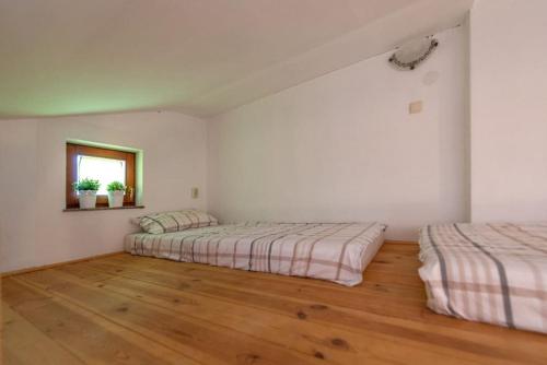 Cette chambre blanche dispose de 2 lits et de parquet. dans l'établissement Studio Apartman Amelie, à Vir