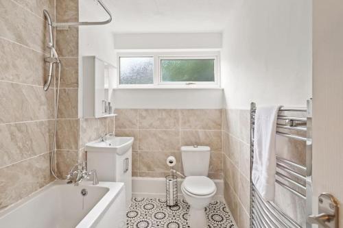 a bathroom with a toilet and a tub and a sink at 10% discount on long stays in Chigwell