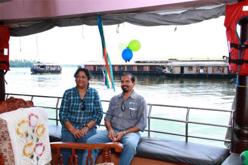 a man and a woman sitting on the back of a boat at Beach Paradise Day Cruise Houseboat in Alleppey