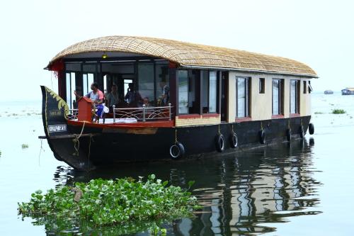 a boat on the water with people on it at Beach Paradise Day Cruise Houseboat in Alleppey